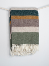 Szary koc wełniany w wielokolorowe pasy z białymi frędzlami.