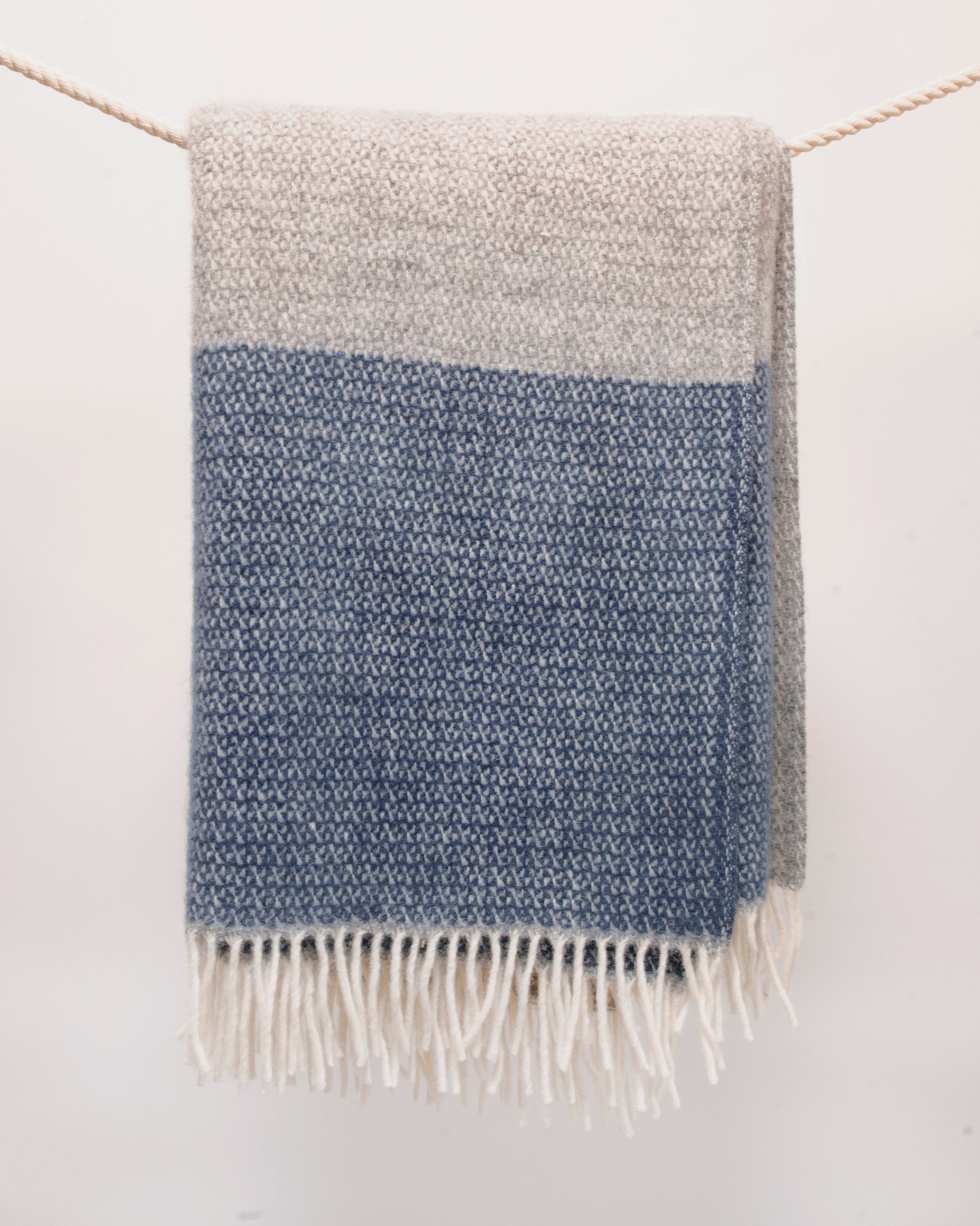 Szary koc wełniany w granatowe pasy z białymi frędzlami